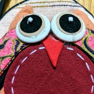 Small beige purse with owl.  Long strap, zip close